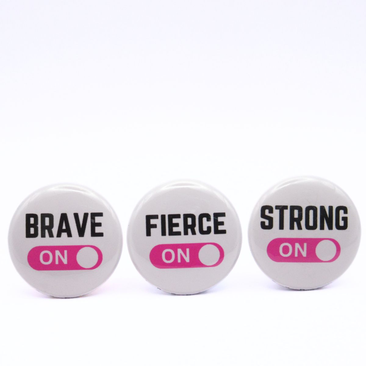 BooBooRoo Pinback Button (i.e. button, badge, pin) 3-pack displaying brave, fierce, and strong modes are on. Pink background for mode indicator.